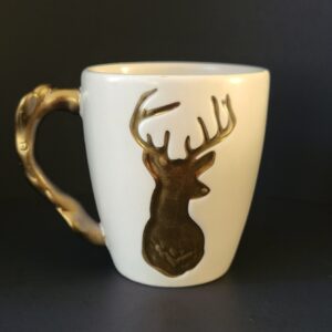 Cream-colored mug with a silver reindeer motif.